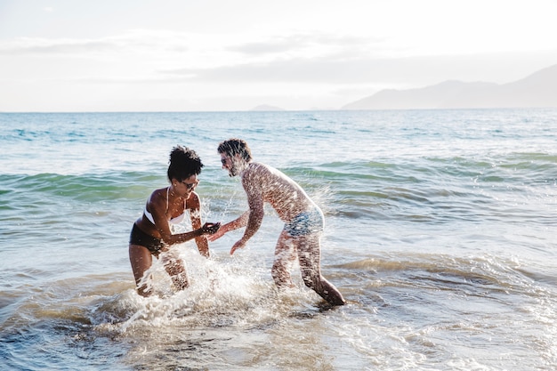 Couple s'amuser dans l'eau à la plage